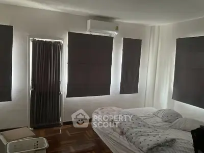 Cozy bedroom with natural light and minimalist decor, featuring a comfortable bed and air conditioning.
