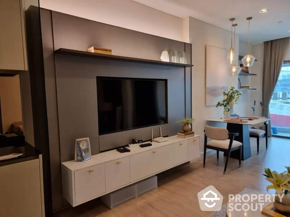 Elegant living room with modern entertainment wall unit, chic pendant lighting, and a cozy dining area, showcasing a blend of style and comfort.