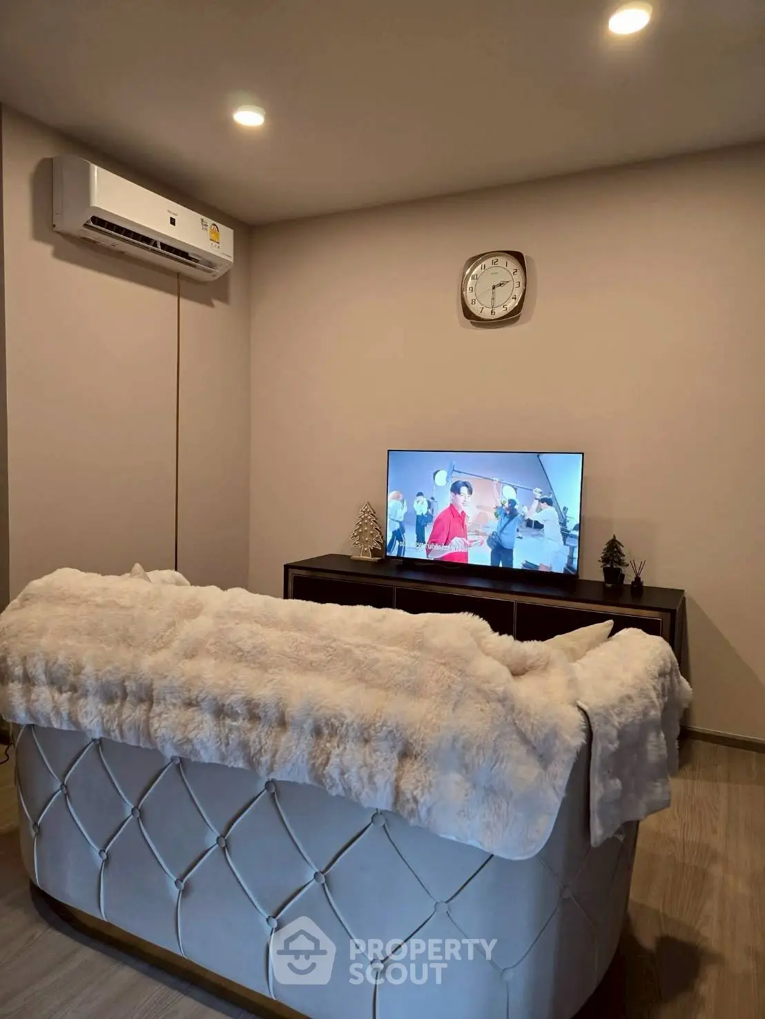 Cozy living room with plush sofa, wall-mounted TV, and modern air conditioning unit.