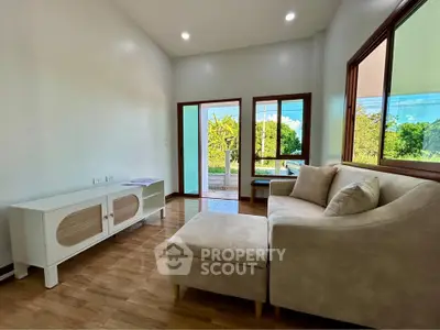 Bright living room with modern sofa and garden view through large windows.
