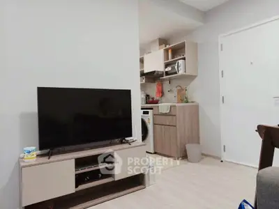 Modern living room with TV and compact kitchen featuring washing machine and open shelving.