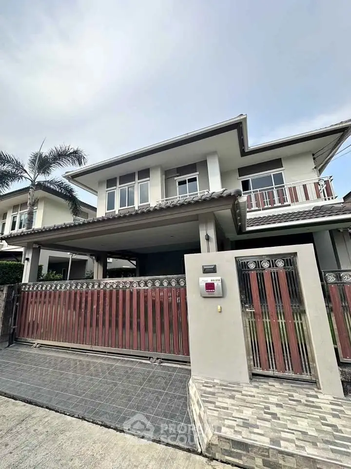 Modern two-story house with gated entrance and tiled driveway in suburban neighborhood.