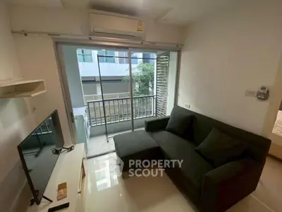 Modern living room with balcony access and sleek black sofa in urban apartment.