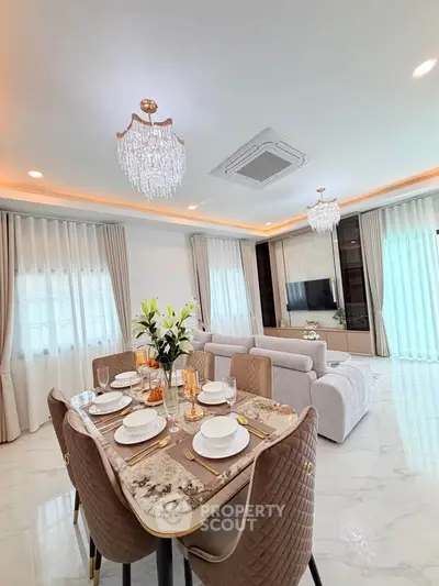 Luxurious open-plan living and dining area with elegant chandeliers and modern decor.