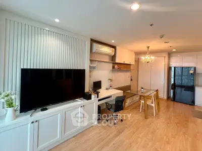Modern living room with stylish decor and open layout, featuring a large TV and elegant dining area.