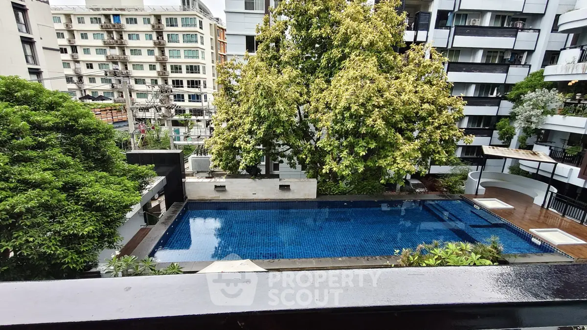 Luxurious residential building with a serene pool surrounded by lush greenery, perfect for relaxation.