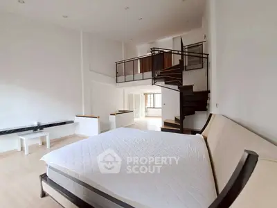 Spacious modern bedroom with loft and spiral staircase in a stylish apartment