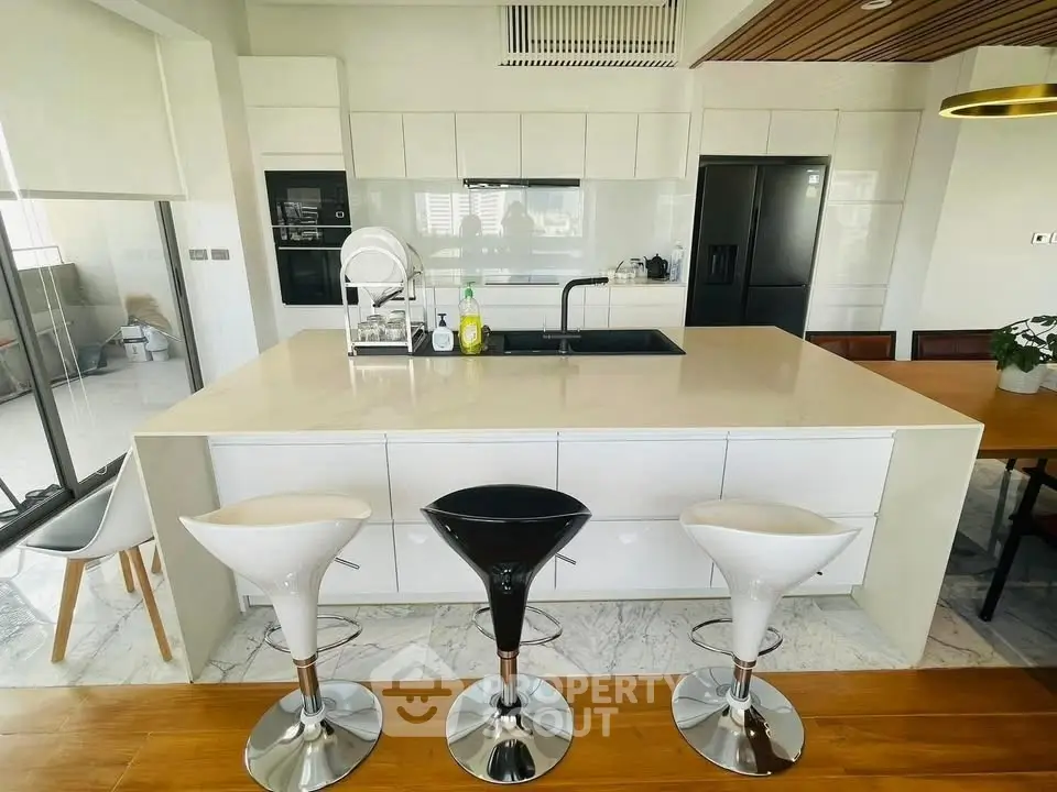 Modern kitchen with sleek island and stylish bar stools in open layout.