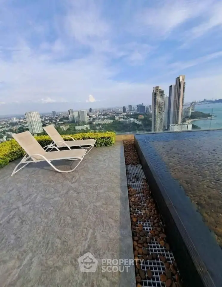 Luxurious rooftop with stunning city and ocean view, featuring elegant lounge chairs and infinity pool.