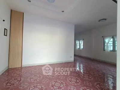 Spacious empty room with patterned tile flooring and natural light from windows.