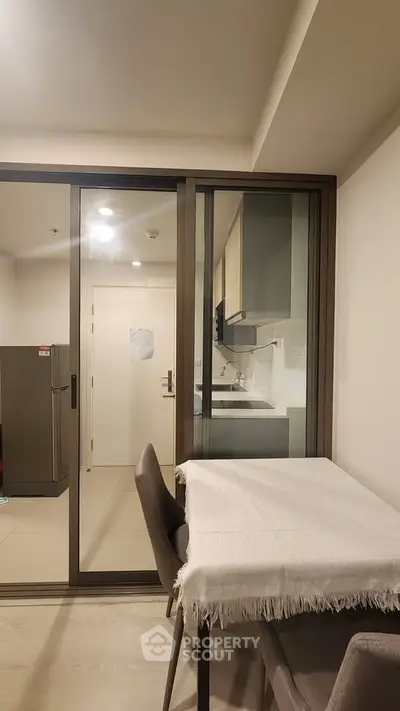 Modern kitchen with sliding glass doors and dining area in a stylish apartment.