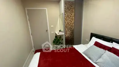 Cozy bedroom with modern decor and red accents, featuring a stylish mosaic wall and plush bedding.