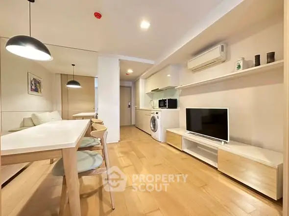 Modern open-plan living room with dining area, featuring sleek furniture and built-in appliances.