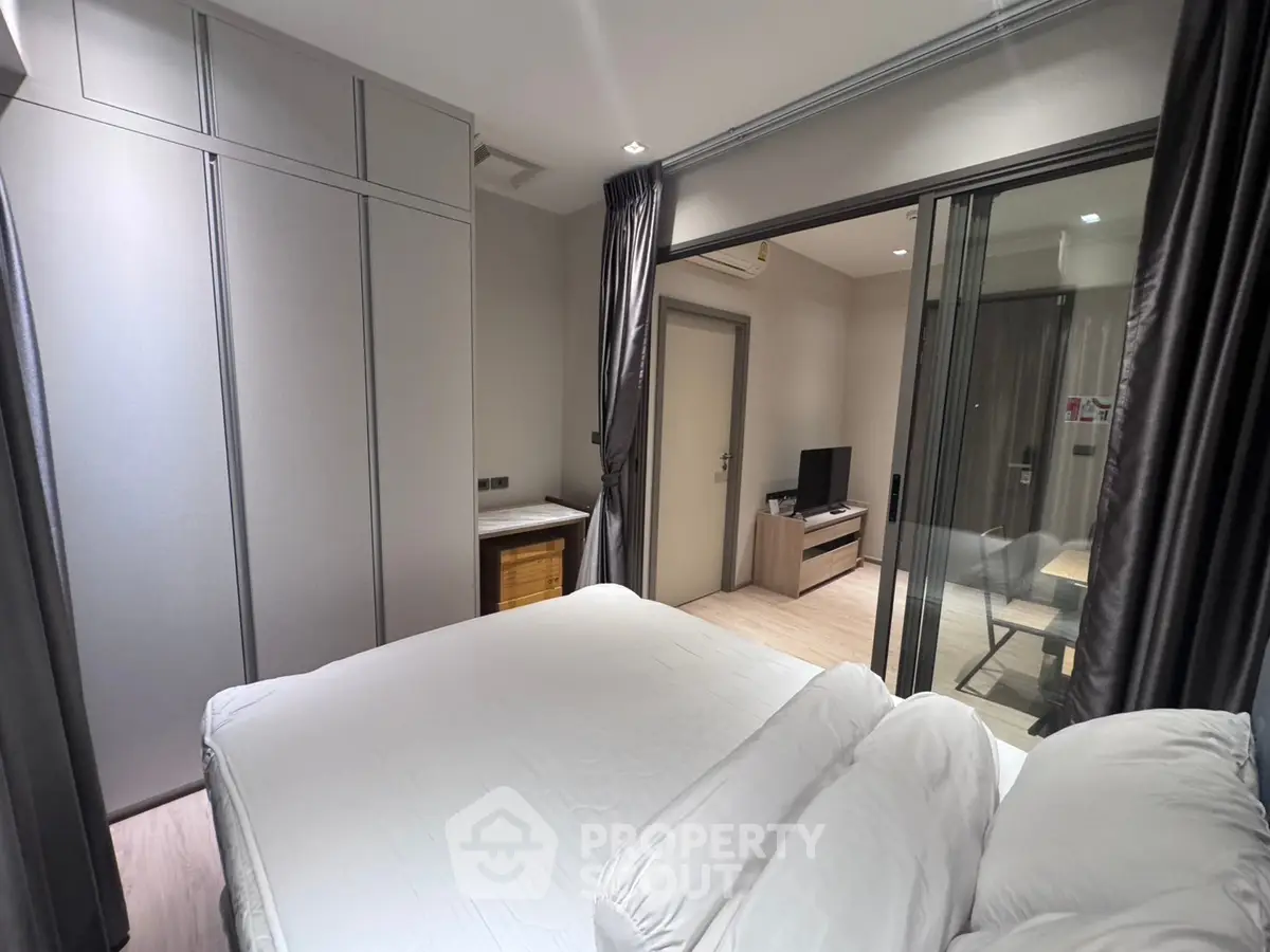 Modern bedroom with sliding glass doors and sleek furniture in a stylish apartment.