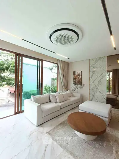 Luxurious living room with modern decor, large windows, and elegant marble accents.