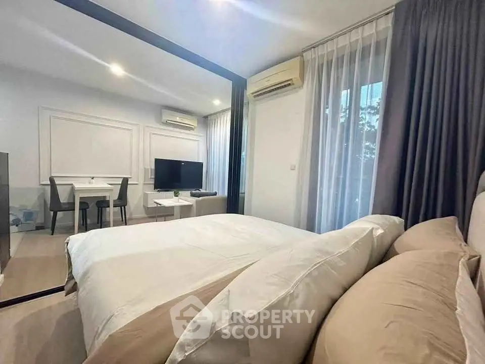Modern bedroom with elegant decor and natural light, featuring a cozy bed and stylish dining area.
