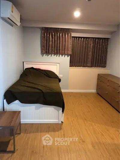 Cozy bedroom with wooden flooring and modern furnishings in a stylish apartment.