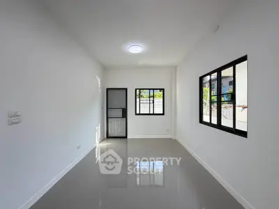 Spacious minimalist room with glossy tiled floor and large windows offering natural light.