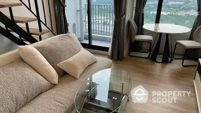 Elegant living space with a plush sofa, glass coffee table, and a charming dining area by the balcony, offering a blend of comfort and style.