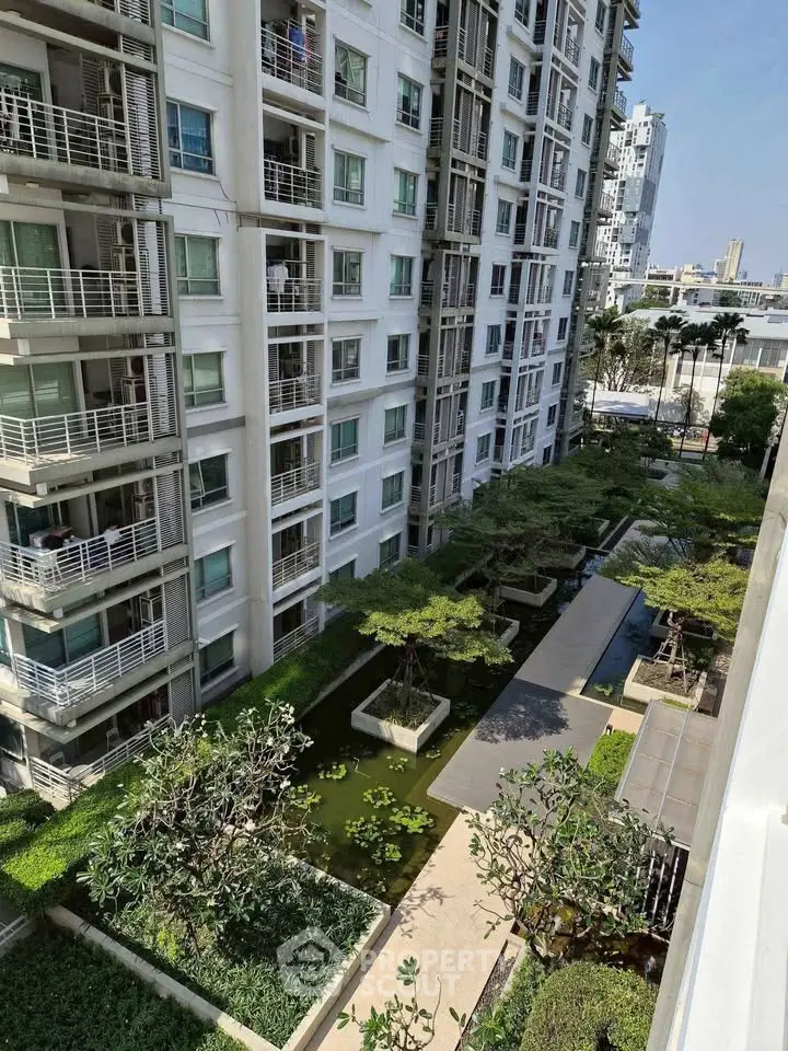 Modern apartment building with lush garden view and serene outdoor space.