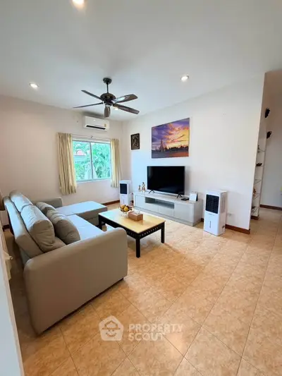 Spacious living room with modern decor and natural light, featuring a comfortable sofa and entertainment center.