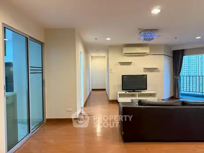 Spacious living room with modern decor and balcony view in a high-rise apartment.