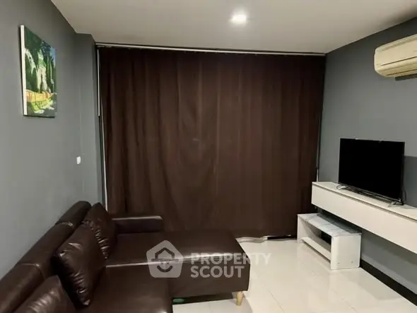 Modern living room with dark leather sofa and wall-mounted TV, featuring sleek design and cozy ambiance.