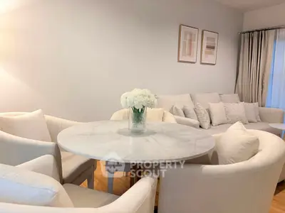 Elegant living room with white furniture and round marble table, perfect for modern living.
