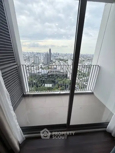 Stunning cityscape view from a modern high-rise balcony with glass doors and sleek design.