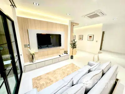 Modern living room with sleek design and large TV, featuring cozy seating and elegant decor.