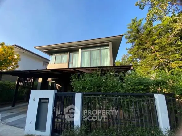 Modern two-story house with large windows and lush greenery, perfect for serene living.