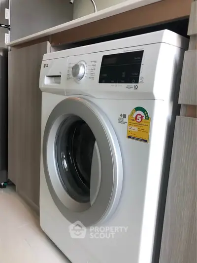 Modern washing machine in sleek kitchen setting with wood cabinetry.