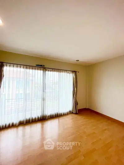 Spacious empty room with large windows and wooden flooring, perfect for customization.