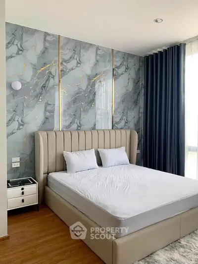 Luxurious bedroom with elegant marble accent wall and plush bed in modern apartment.