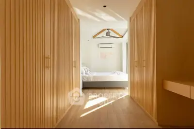Spacious bedroom with wooden accents and natural light, featuring a cozy bed and modern design.