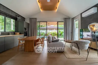 Modern open-plan living room with stylish kitchen and garden view, featuring elegant furniture and natural light.