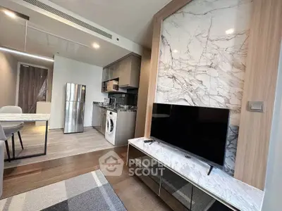Modern open-layout living room with kitchen, featuring marble accents and sleek appliances.