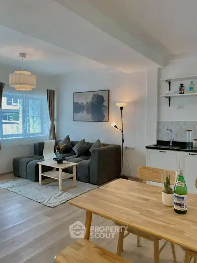 Modern open-plan living room with cozy seating and dining area, featuring stylish decor and natural light.