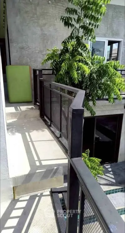 Modern balcony with sleek railing and lush greenery, offering a serene outdoor space.
