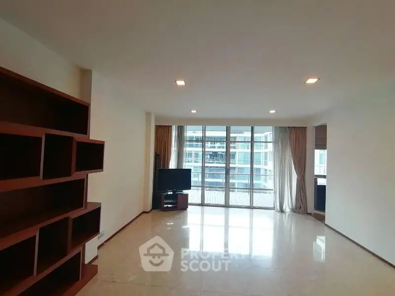 Spacious living room with large windows and built-in shelving, offering a bright and airy atmosphere.