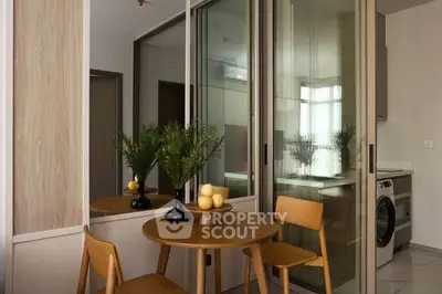 Modern dining area with wooden table and chairs, adjacent to a sleek kitchen with washing machine.