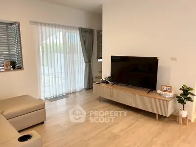 Modern living room with sleek TV stand, large windows, and stylish decor.