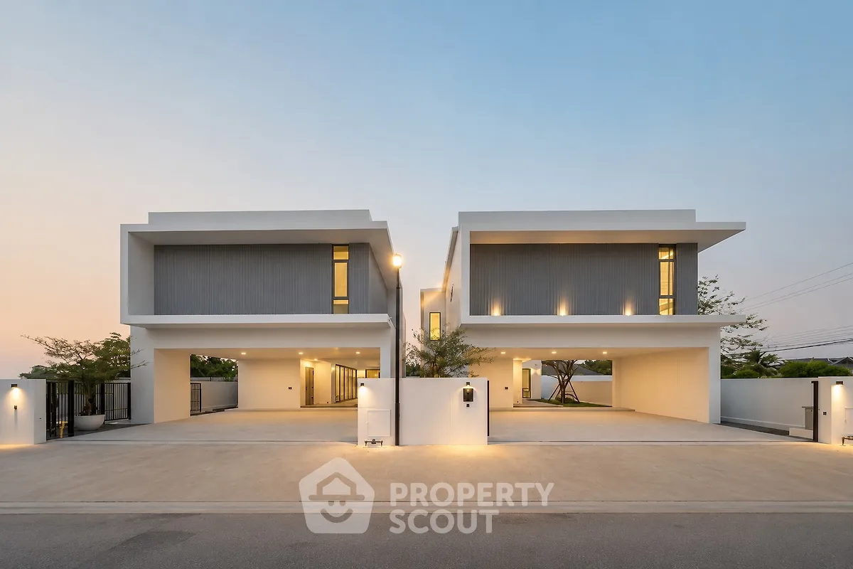 Modern luxury duplex with sleek design and spacious driveway at sunset.