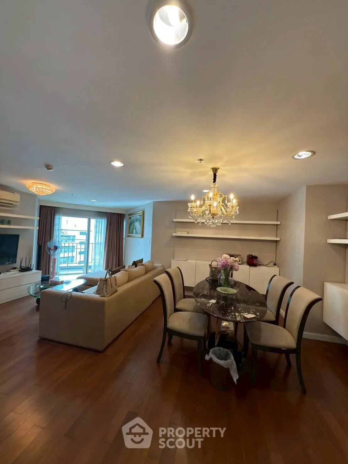 Spacious living room with elegant chandelier and dining area in modern apartment.