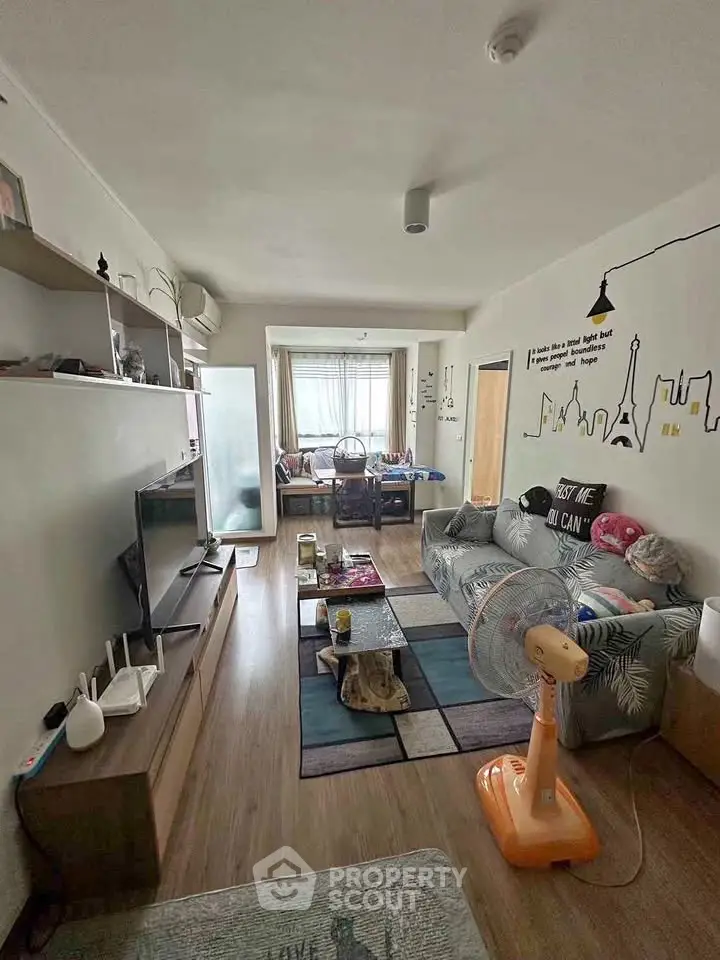 Cozy living room with modern decor and ample natural light, featuring a stylish sofa and entertainment area.