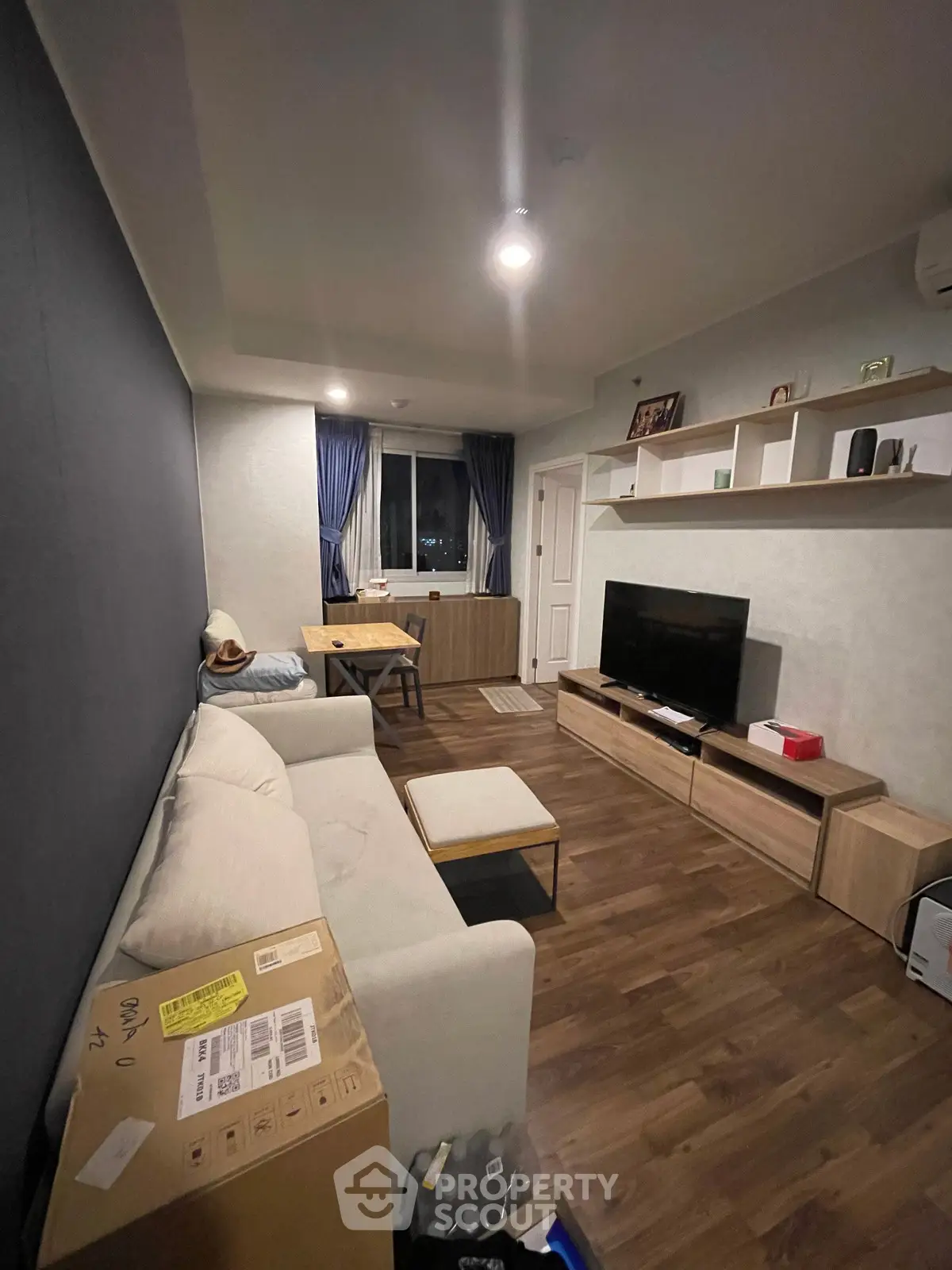 Modern living room with cozy sofa, TV unit, and stylish decor in a well-lit apartment.