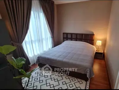 Cozy bedroom with elegant decor and natural light, featuring a stylish bed and modern lamp.