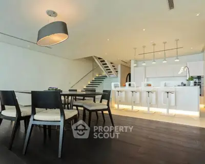 Luxurious open-plan kitchen and dining area with modern lighting and sleek design.