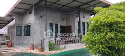 Modern concrete house with lush greenery and covered porch, offering a serene and stylish living environment.