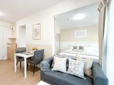 Modern open-plan living room with dining area and cozy bedroom in a stylish apartment.